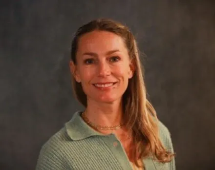 Photo of Amanda Merck in a green sweater against a dark backdrop