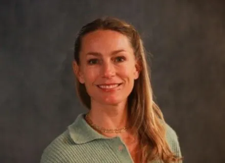 Photo of Amanda Merck in a green sweater against a dark backdrop