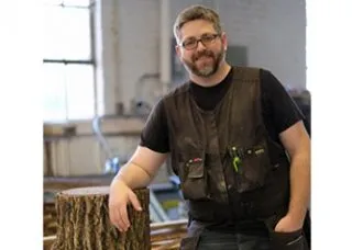 Lowell Miller with a tree stump in the fabrication shop