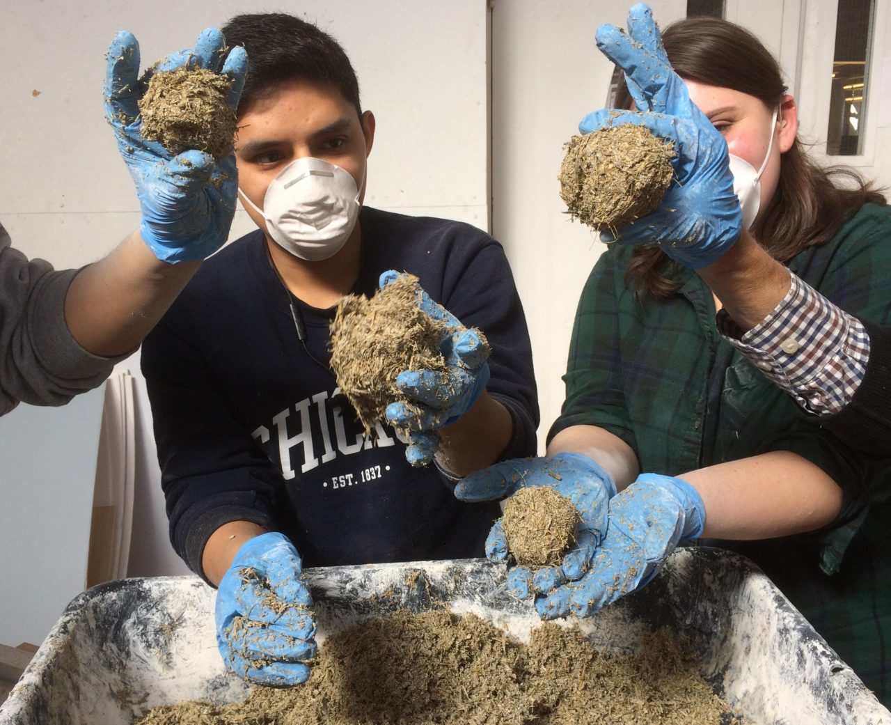 Students in masks holding building materials 