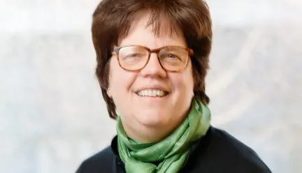 headshot of kathleen jaems holding a gold coin 