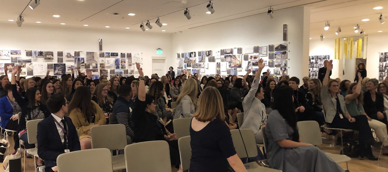 audience members raising hands at the symposium 