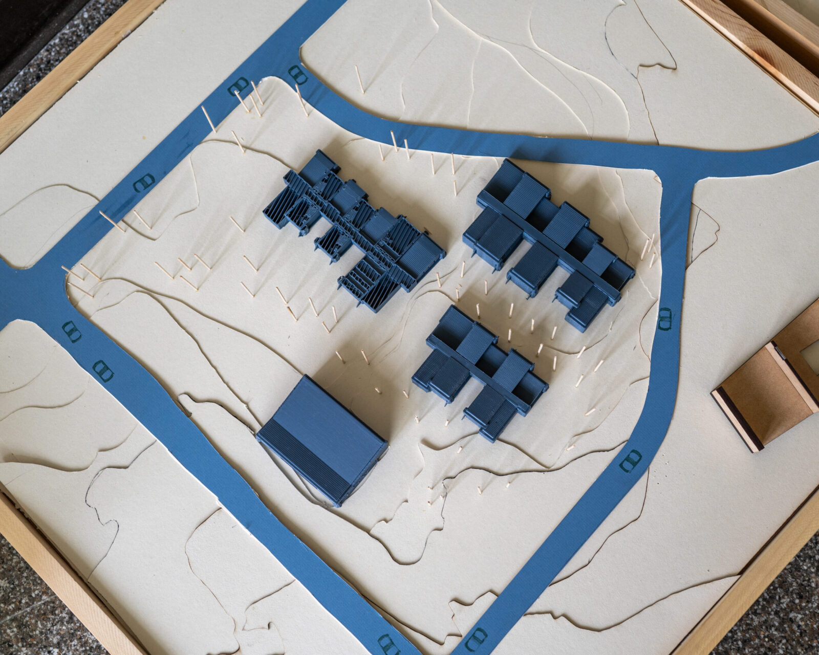 Small blue scaled buildings with blue roads and landscaping carved into paper