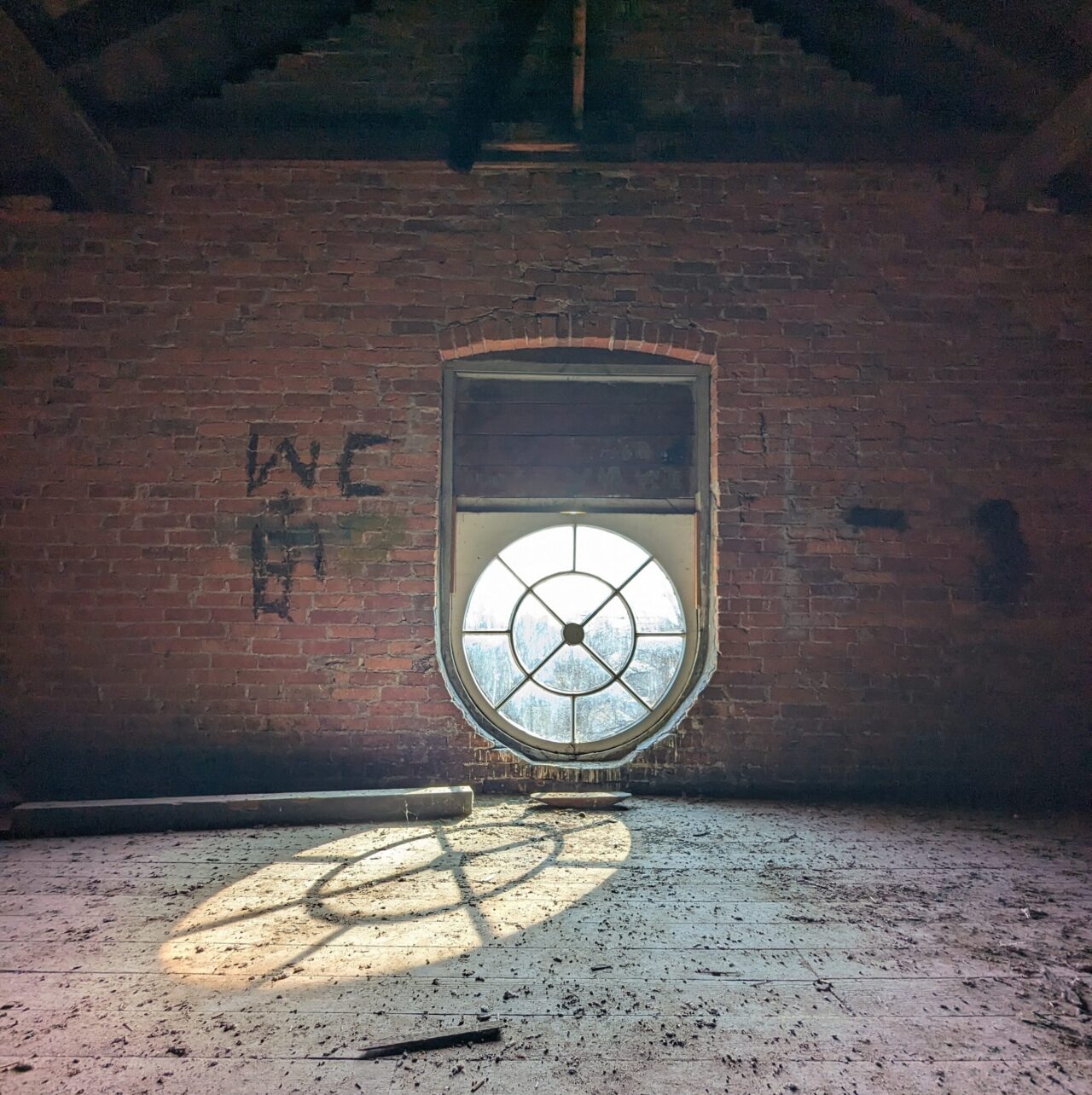 attic of Old East School, brown brick, dirty, circular window, graffiti