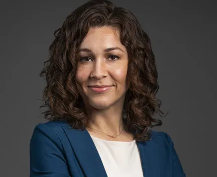 shoulder length curly hair, smiledat camera, crossed arms, blue blazer, white top