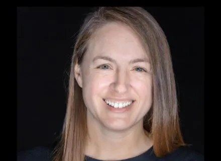 white complexion woman smiling, chest length hair, right ear showing, blue shirt