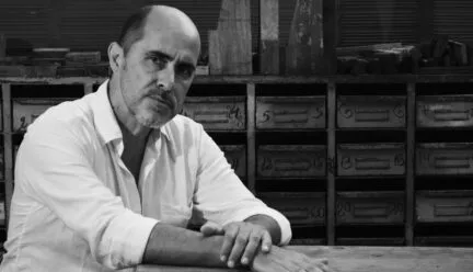 two men in a combined photograph, one on the left looking into the distance with a shadow, the other sitting at the desk with books behind him