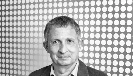 black and white picture man staring intensely into camera wearing a polo shirt black hair