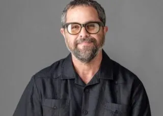 man in black shirt in photo smiling at camera beard and short hair