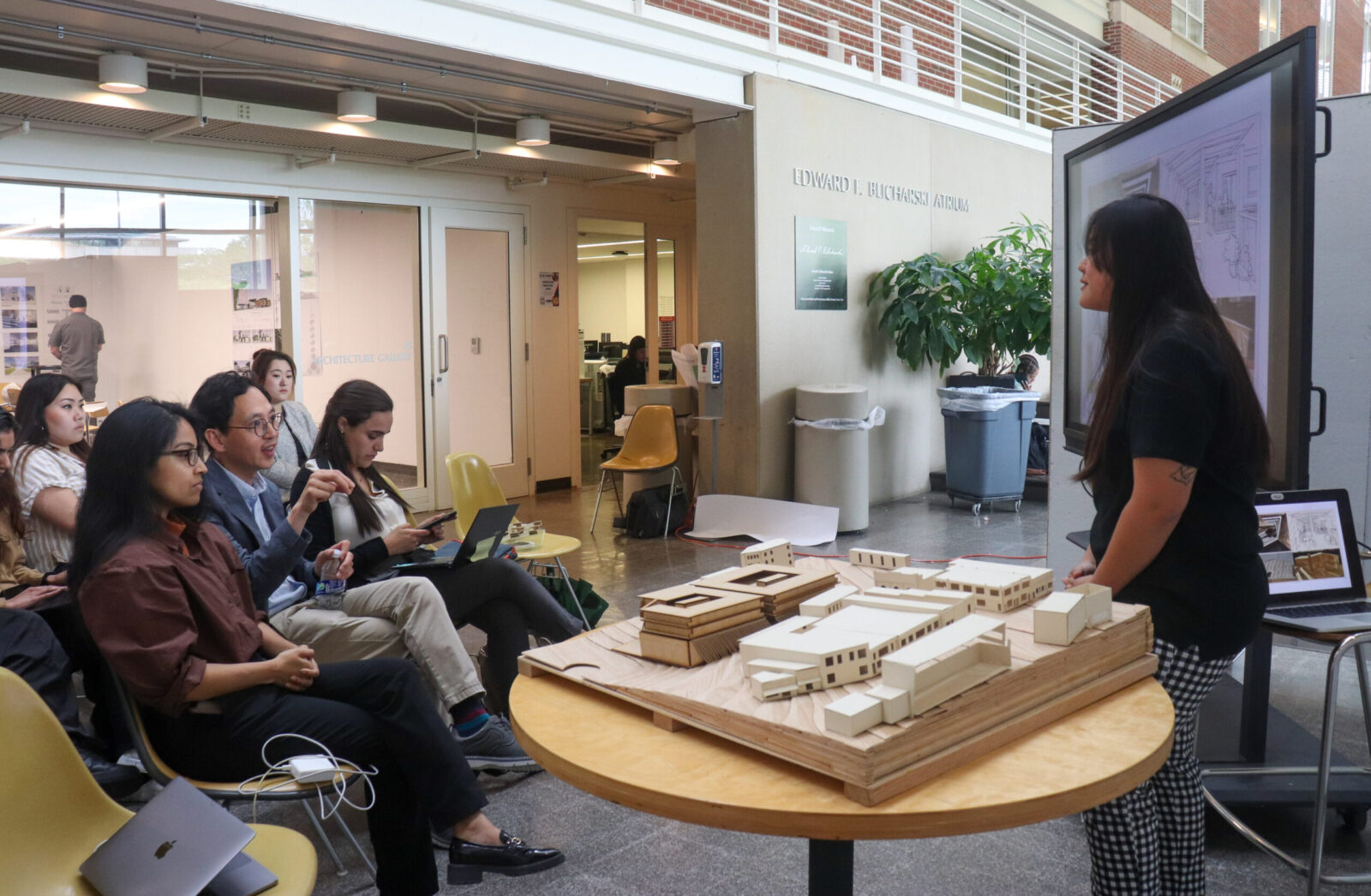 a student in front of an audience with a building model