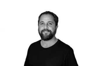 man in black tshirt in black and white photo smiling at camera beard and short hair
