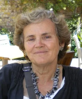 woman smiling into camera, short blonde hair, black and white necklace, tan complexion