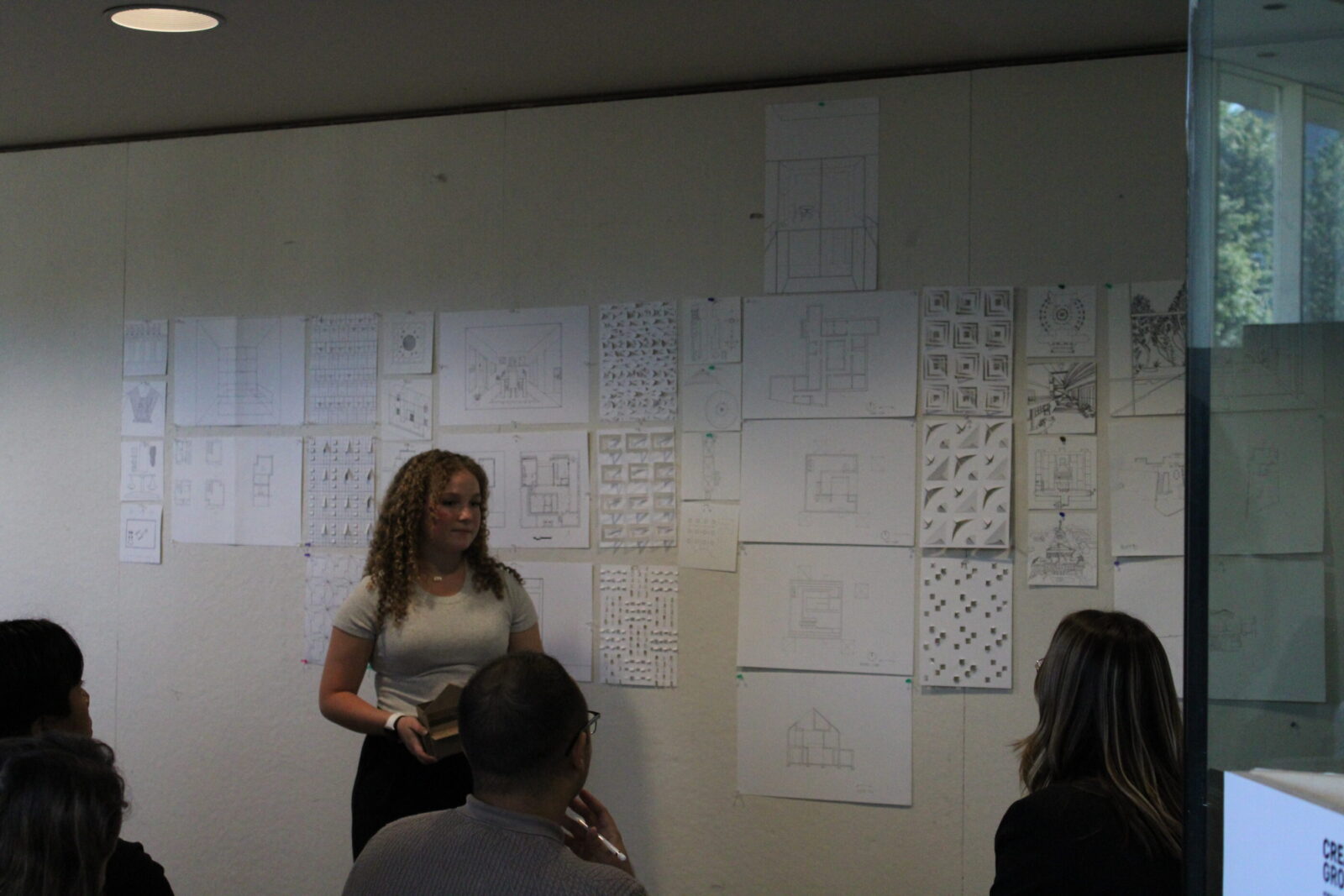 a student in front of posters pinned up on a wall