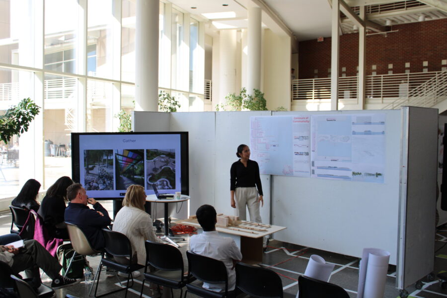 a student presenting posters and a tv in front of an audience