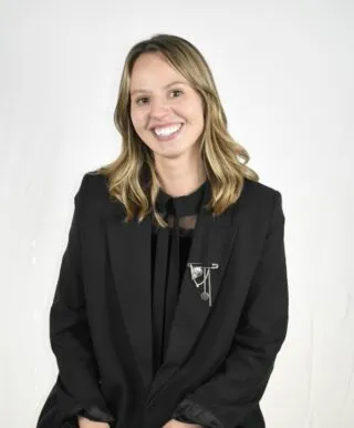 white woman tan blonde hair black suit smiling hair blowing in wind
