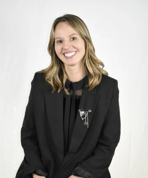 white woman tan blonde hair black suit smiling hair blowing in wind