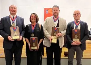 4 professors looking at the cemera and smiling