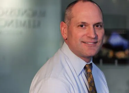 man turning to right looking at camera balding with white shirt and tie smling 