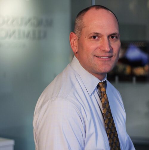 man turning to right looking at camera balding with white shirt and tie smling 
