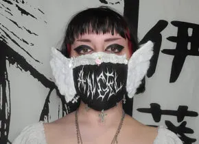 Woman wearing a black mask with a white pattern and white wings  