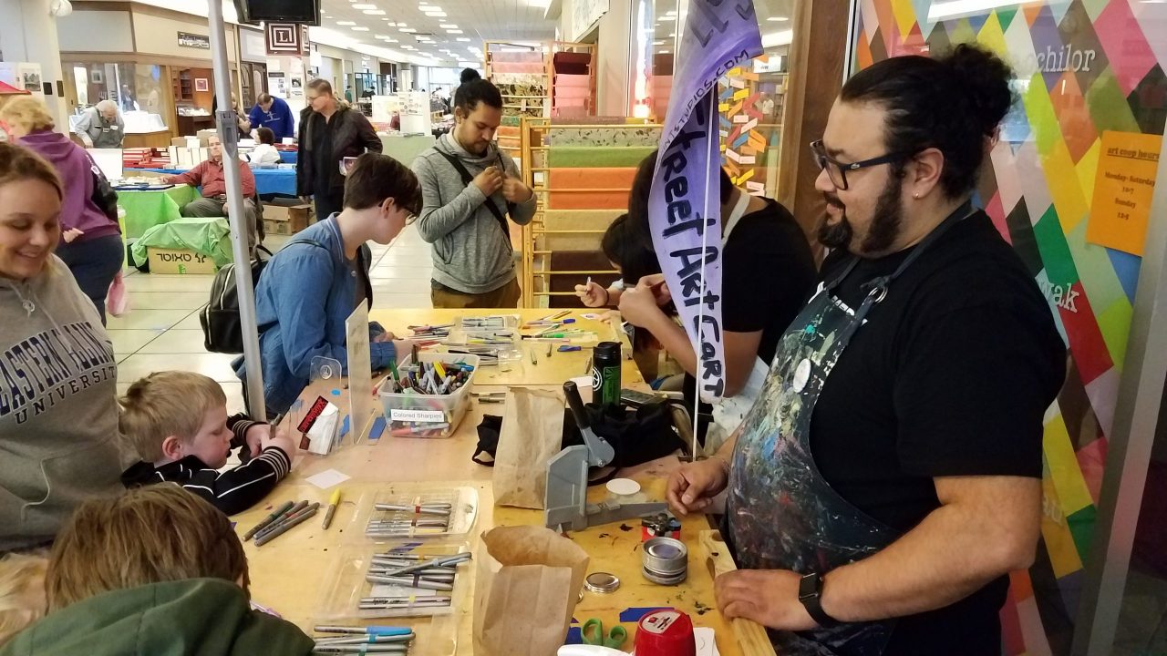 Photo of schoolchildren and young adults making art at a booth