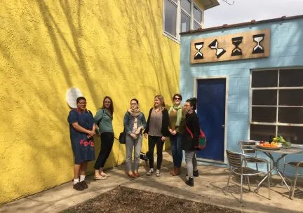 Photo of a group of doctoral students outdoors before a yellow wall