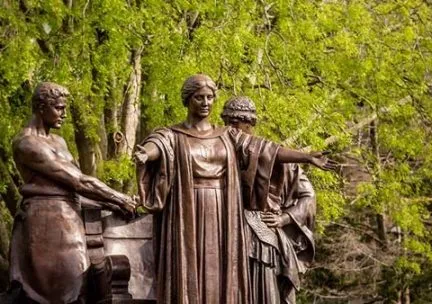 Photo of the Alma Mater statue group with green trees in the background