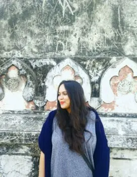 Portrait of the smiling student standing before a textured architectural surface