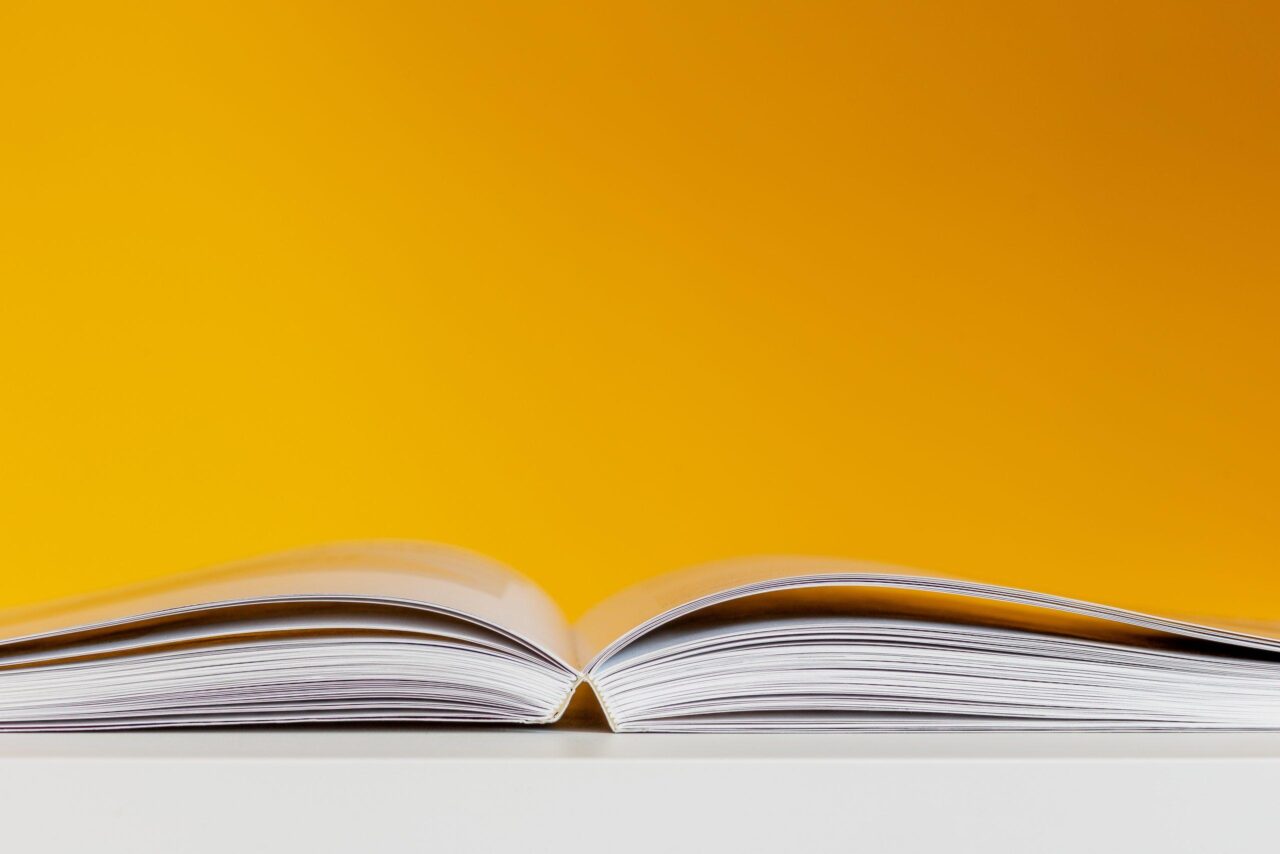 Eye-level view of an open book against a yellow background