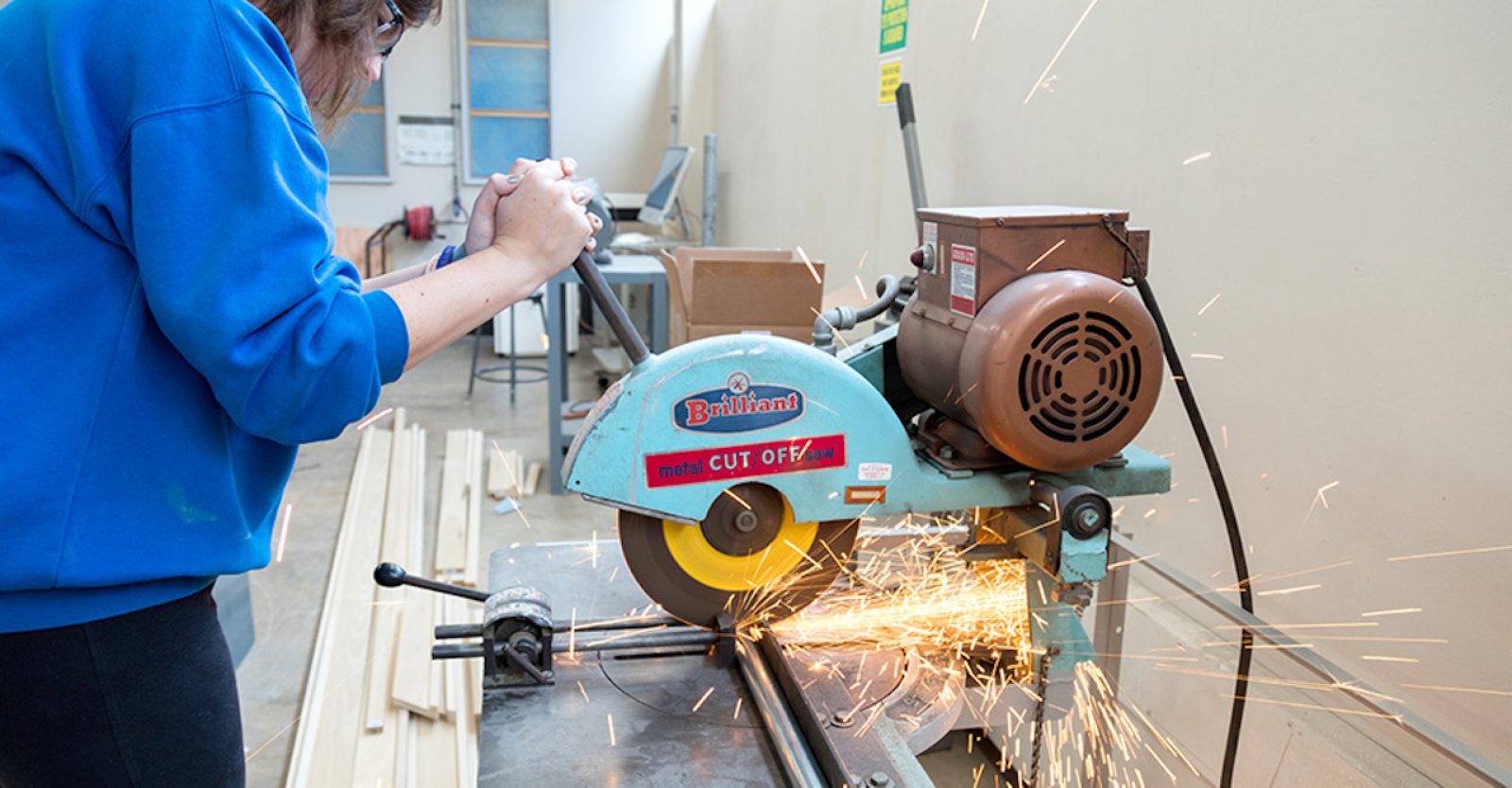 student cuts metal bar with a grinder, sparks fly