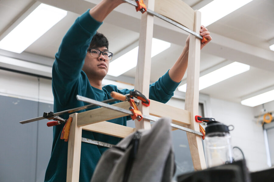 student applies clamps to a wooden chair he is making