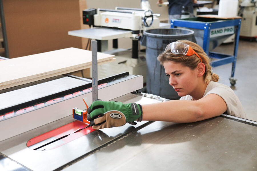 female student measures the blade height on a tablesaw 