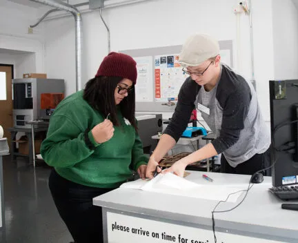 student worker assists student with weeding vinyl at the Service Desk