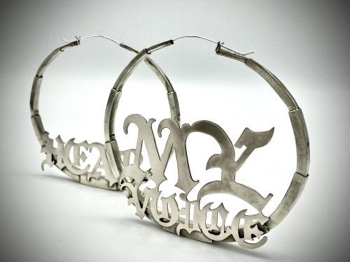 Photo of brass hoop earrings that spell out the words "hear my voice"