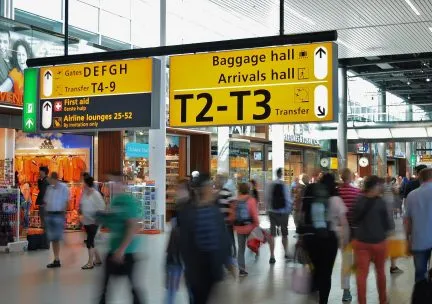 Photo of people in an airport with a baggage claim sign overhead