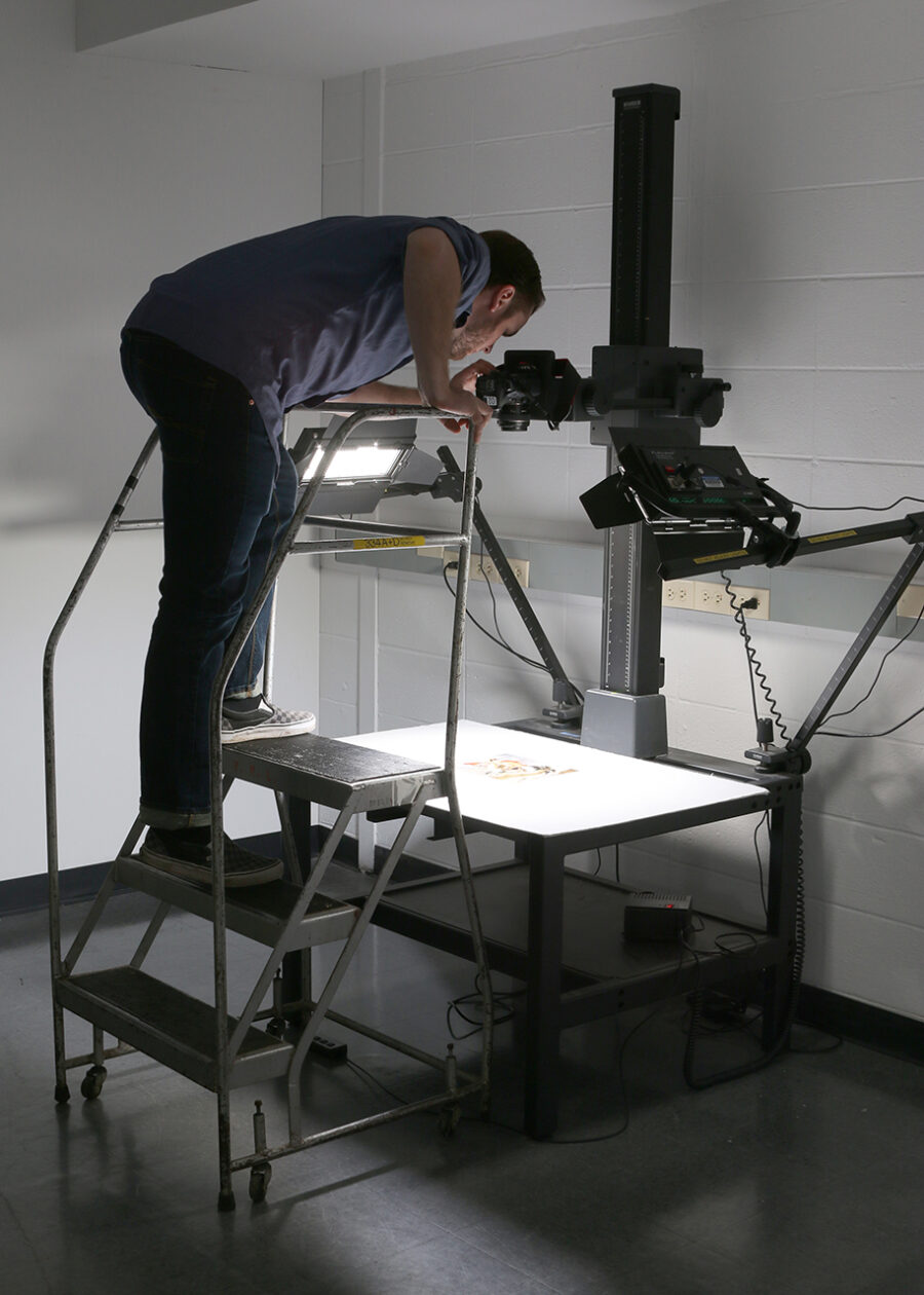 person on step ladder using copy stand to document artwork