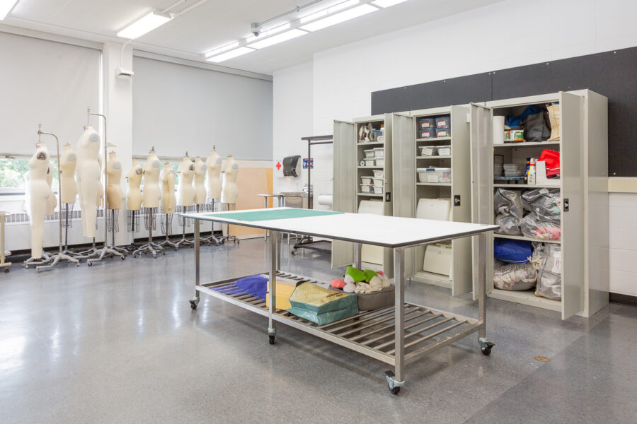 large worktable with cabinets of sewing supplies and dress forms