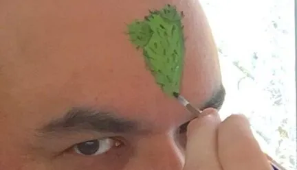 portrait of Jorge Lucero's forhead being painted a green triangle