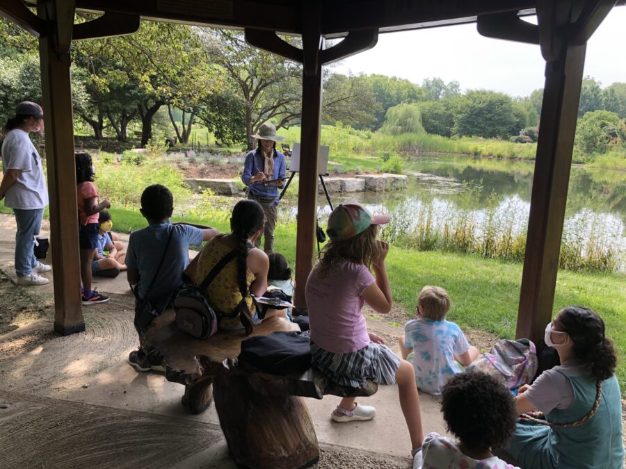 children watching a teacher doing a painting demo at the Japan House