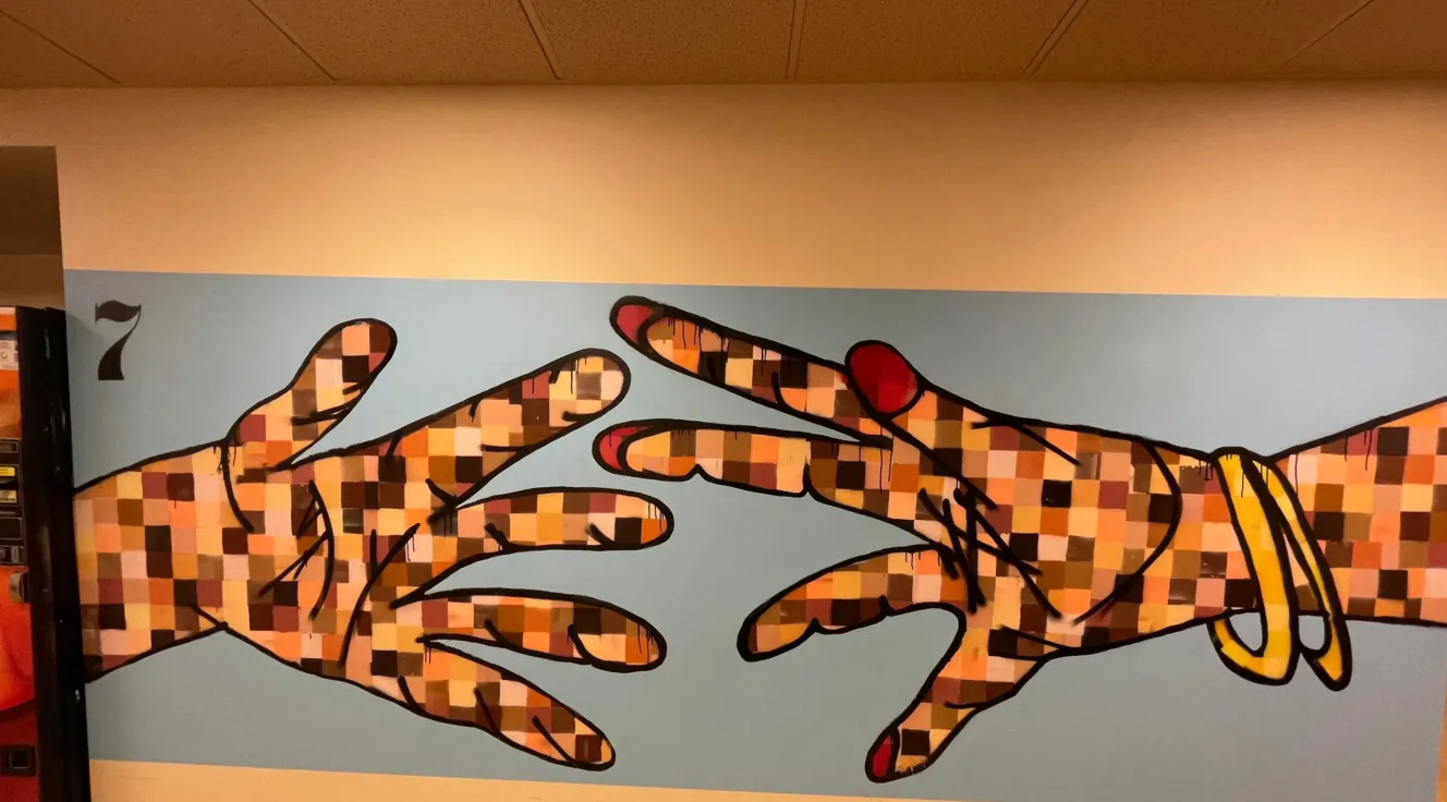 Graffiti mural of two hands reaching for each other