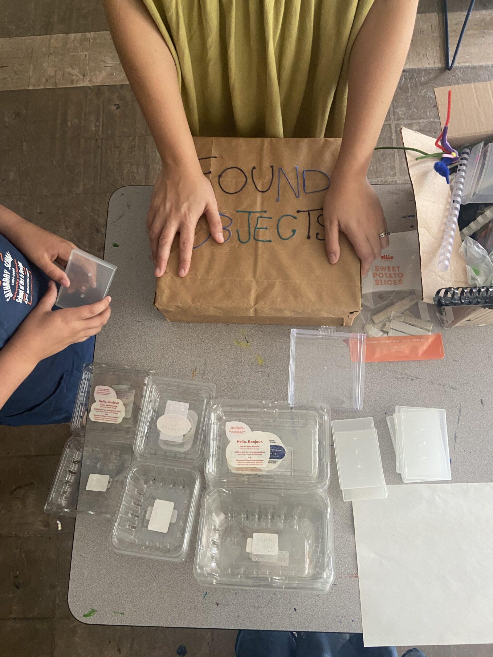 a teacher holding a box that says "found objects"