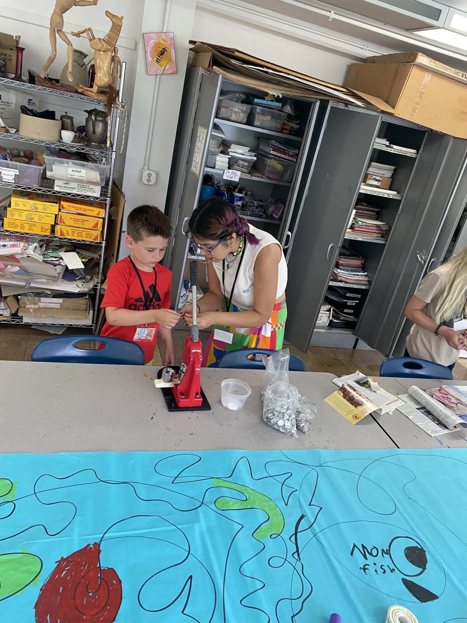 a teacher helping a student make a button