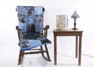 Installation with quilt, rocking chair, photo book, and table