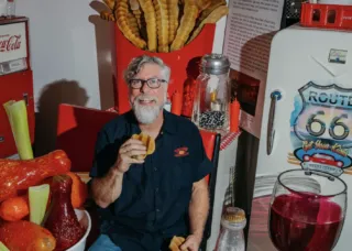 Man sitting in the centre of larger than life sculptures of food