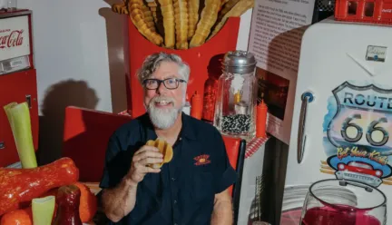 Man sitting in the centre of larger than life sculptures of food