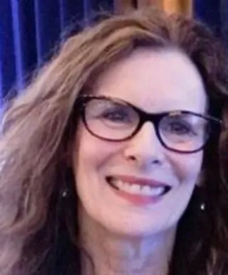 A headshot of Rebecca, wearing a bright orange scarf