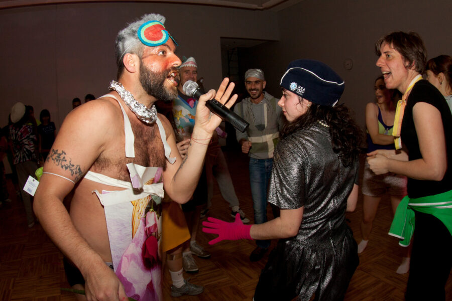 Miguel holding a microphone and in costume along with students in costume