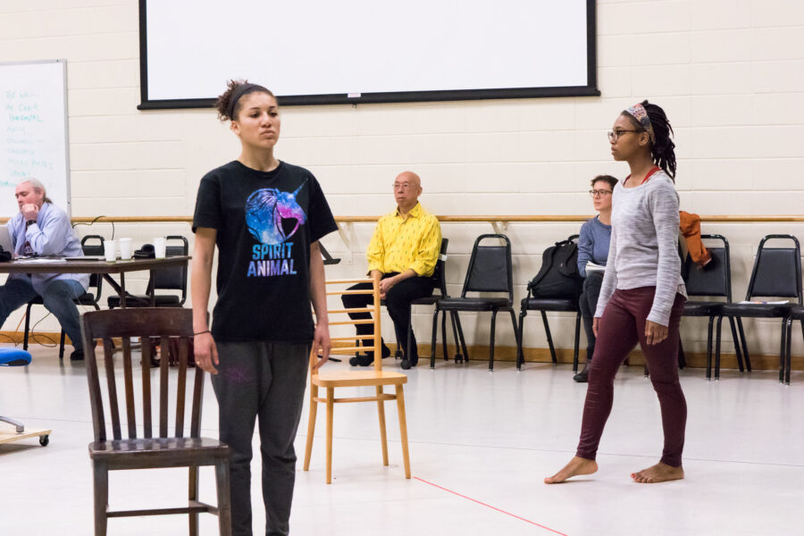 Two dancers in the foreground and guest artist sitting in the background observing