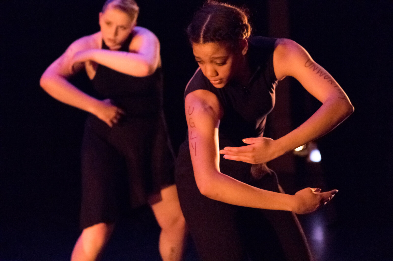 two dancers with "ugly" text written on one arm