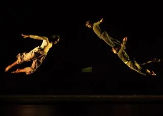 Three dancers flying through the air on stage